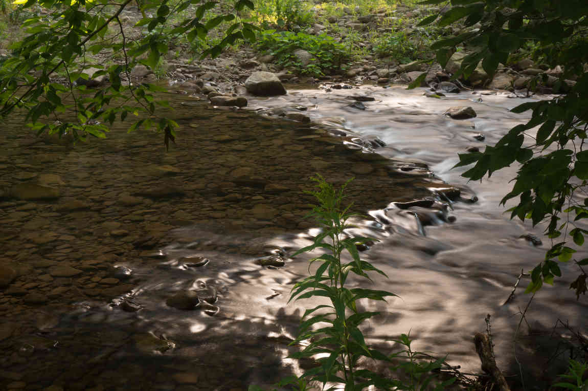 a small river captured with a slow shutter giving it a glassy appearance